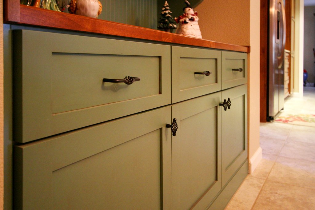 Sage green shaker-style cabinetry with bronze handles