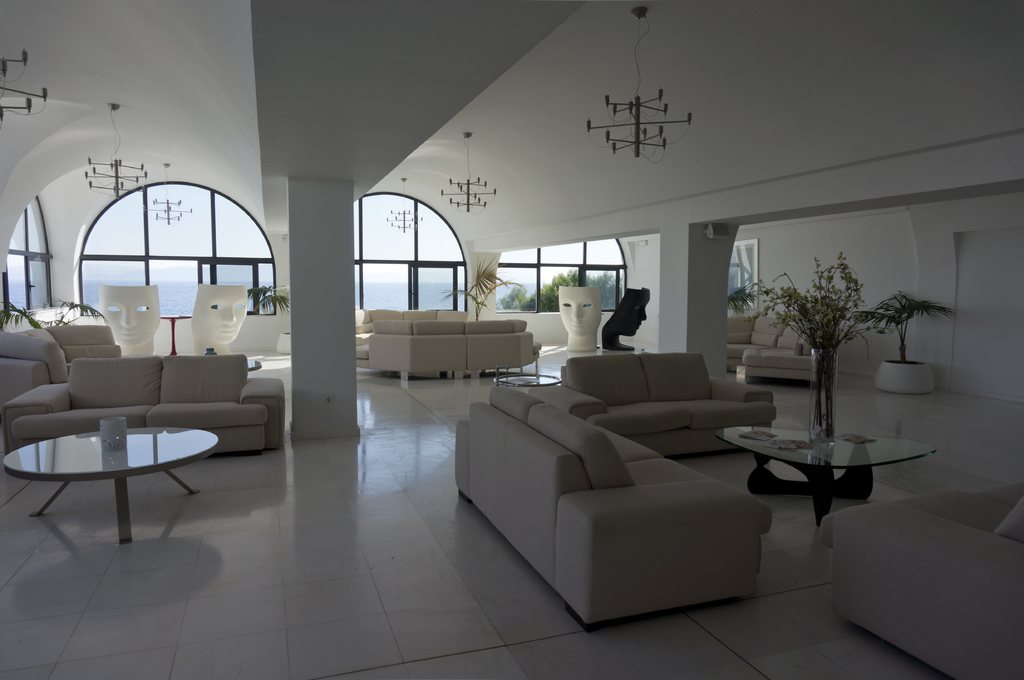 Bright open-plan living space with white sofas, glass tables and tall arched windows