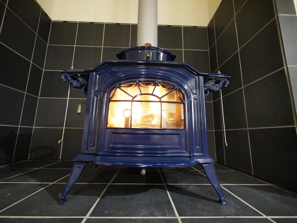 Enamel wood stove on a tiled hearth with a stainless flue
